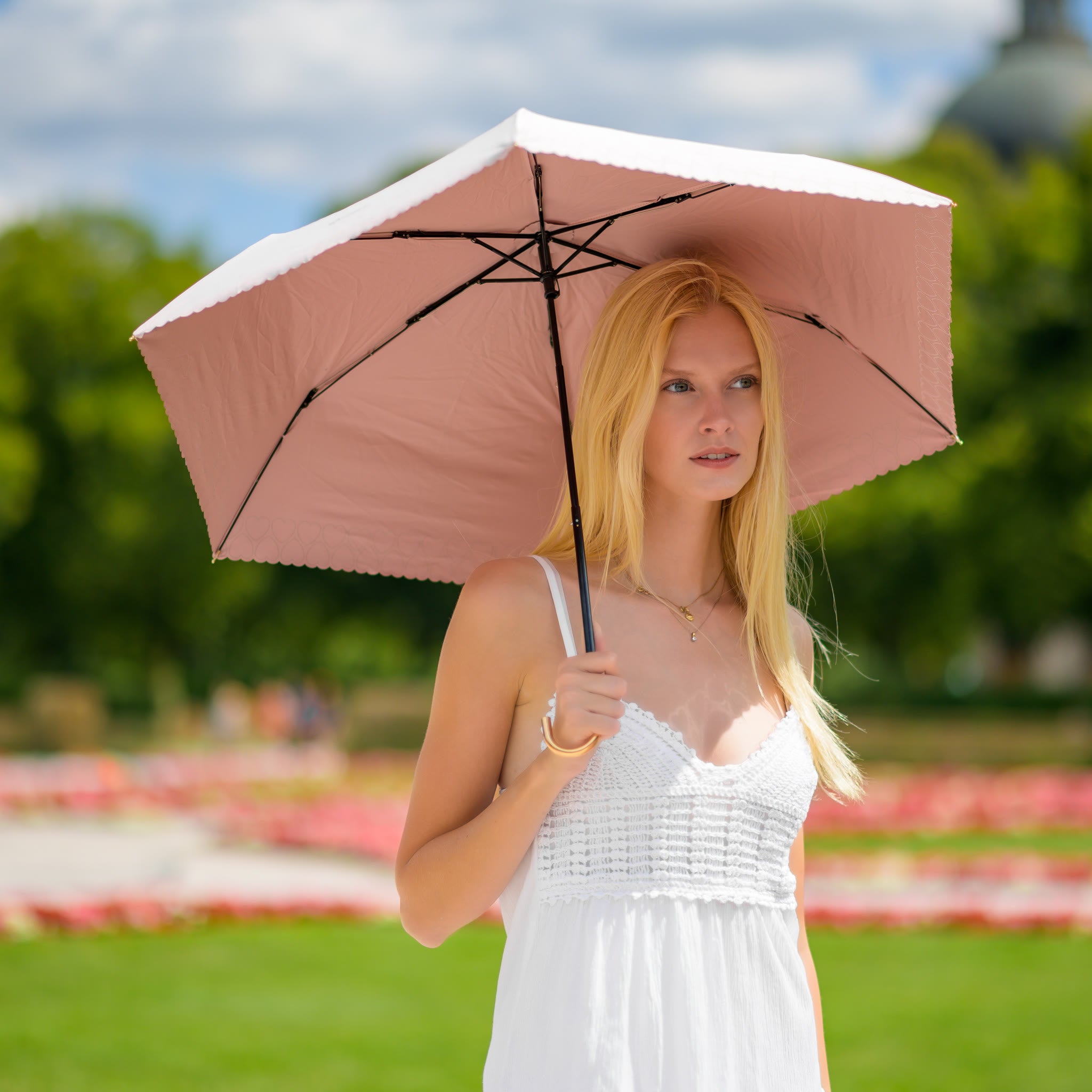 Woman with the Sunbarry Romantic Breezer in Blush Rosé in the park – UV umbrella with heart trim and gold handle#Color_Blush Rosé